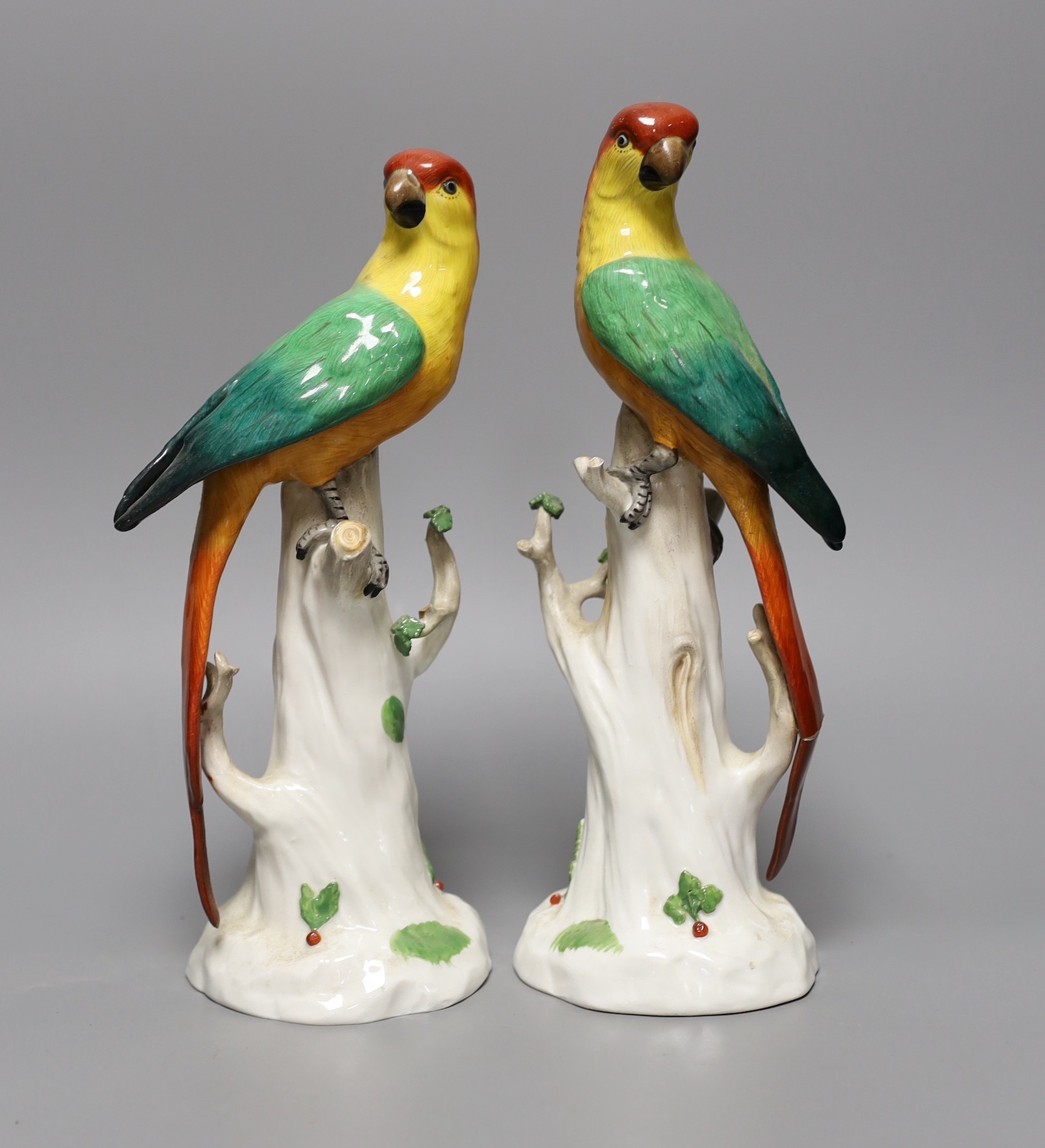 A pair of Continental porcelain perching parrots, 25cm tall